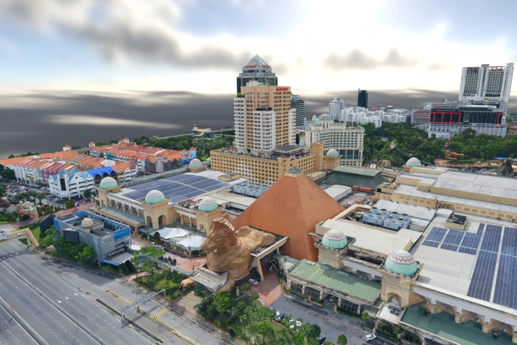 Textured 3D reality mesh of a Malaysian township, with modelled tower blocks, mall roofs, solar arrays and a dual carriageway